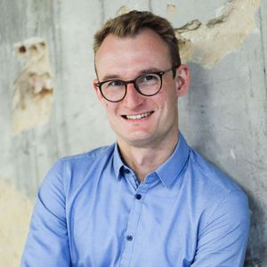 Portraitfoto von Henry Steinbach, lächelnder junger Mann mit Brille in hellblauem Hemd